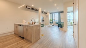 A modern kitchen with a dishwasher, a central island, and a dining area with a green sofa and a small table.