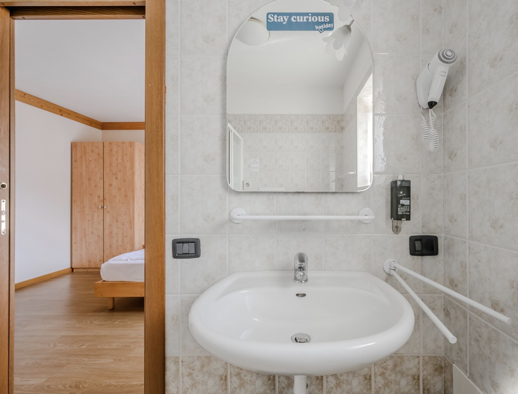 A bathroom with a white sink, a mirror, a hairdryer, and a towel rack.