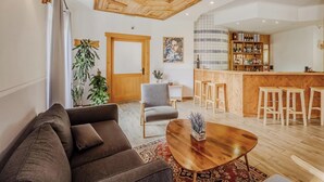 A modern living room with a wooden ceiling, a bar area with stools, and a large mirror. - Hotiday Bormio Valdidentro (San Carlo)