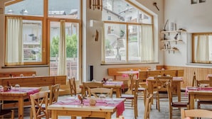 A spacious dining area with large windows, wooden furniture, and a rustic interior design. - Hotiday Bormio Valdidentro (San Carlo)