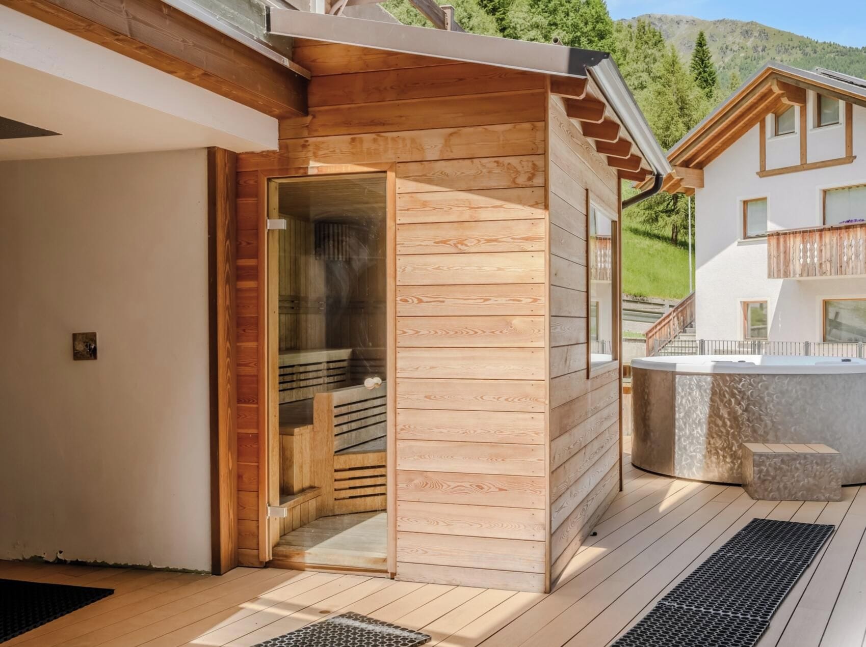 Eine Holzsagone mit Glastür, neben einem modernen Gebäude mit Balkon.