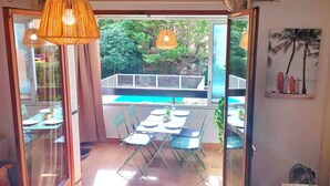 A dining area with a table set for four, a view of a pool, and a balcony with a railing. - Flat with terrace in Sanary-sur-Mer (Sanary-sur-Mer)