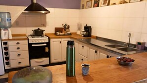Et køkken med hvide skabe, en komfur, en kaffemaskine og en vask.