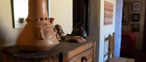 Un aparador de madera con una maceta de barro grande y pequeñas figurillas encima.