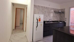 Eine Küche mit Marmorarbeitsplatte, einem Kühlschrank und einem Spülbecken.