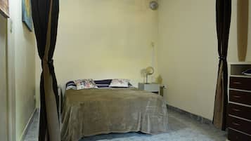 A bedroom with a bed, a nightstand, a lamp, and a wardrobe.