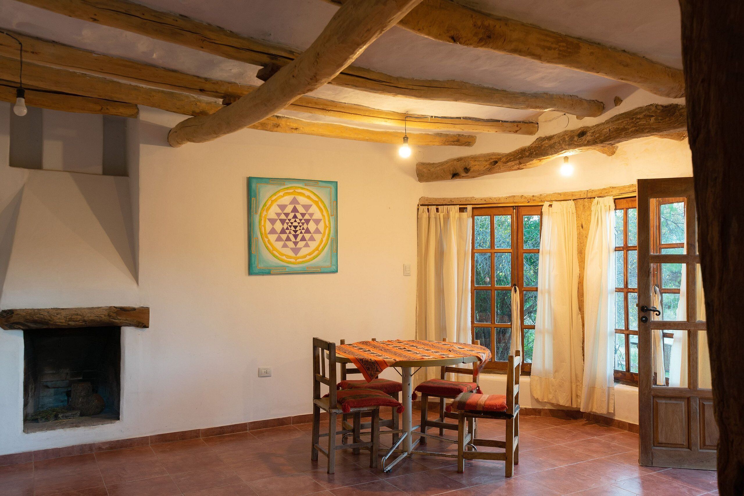 A dining area with a table and chairs, a fireplace, and large windows with curtains.