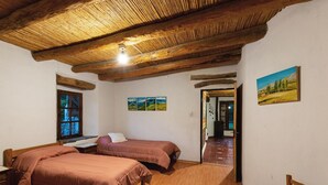 Een kamer met twee bedden, houten vloeren, een houten plafond en een schilderij aan de muur.