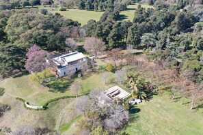 An aerial view of a property with a large building surrounded by trees and open grassy areas.