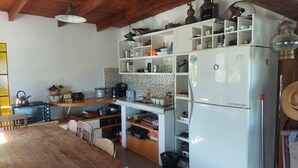 Eine Küche mit Holzbalken, einem weißen Kühlschrank und verschiedenen Küchengeräten.