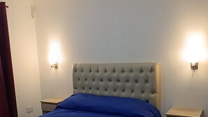 Une chambre à coucher avec un grand lit, deux tables de chevet et des lampes fixées au mur.