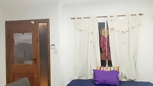 Une chambre moderne avec un canapé, une petite table, un lit recouvert d’une courtepointe bleue et une fenêtre avec des rideaux.