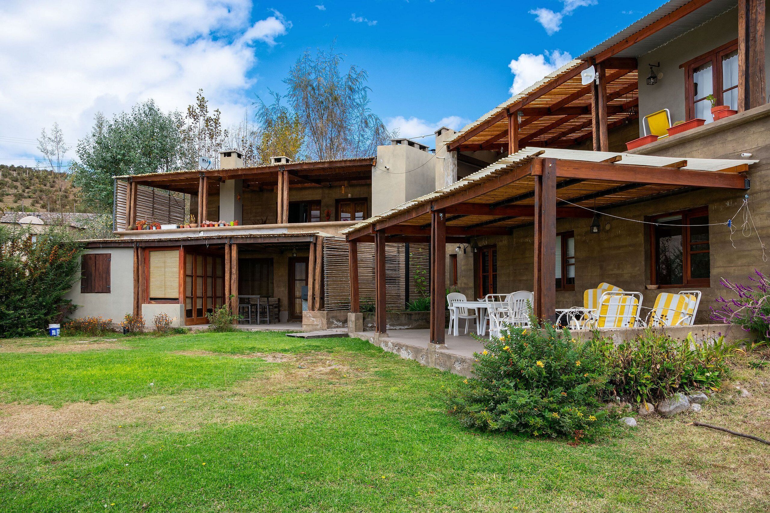 A two-story house with a covered patio, outdoor seating, and a garden.