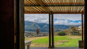 Un espacio al aire libre techado con vistas a montañas y un pueblo lejano.