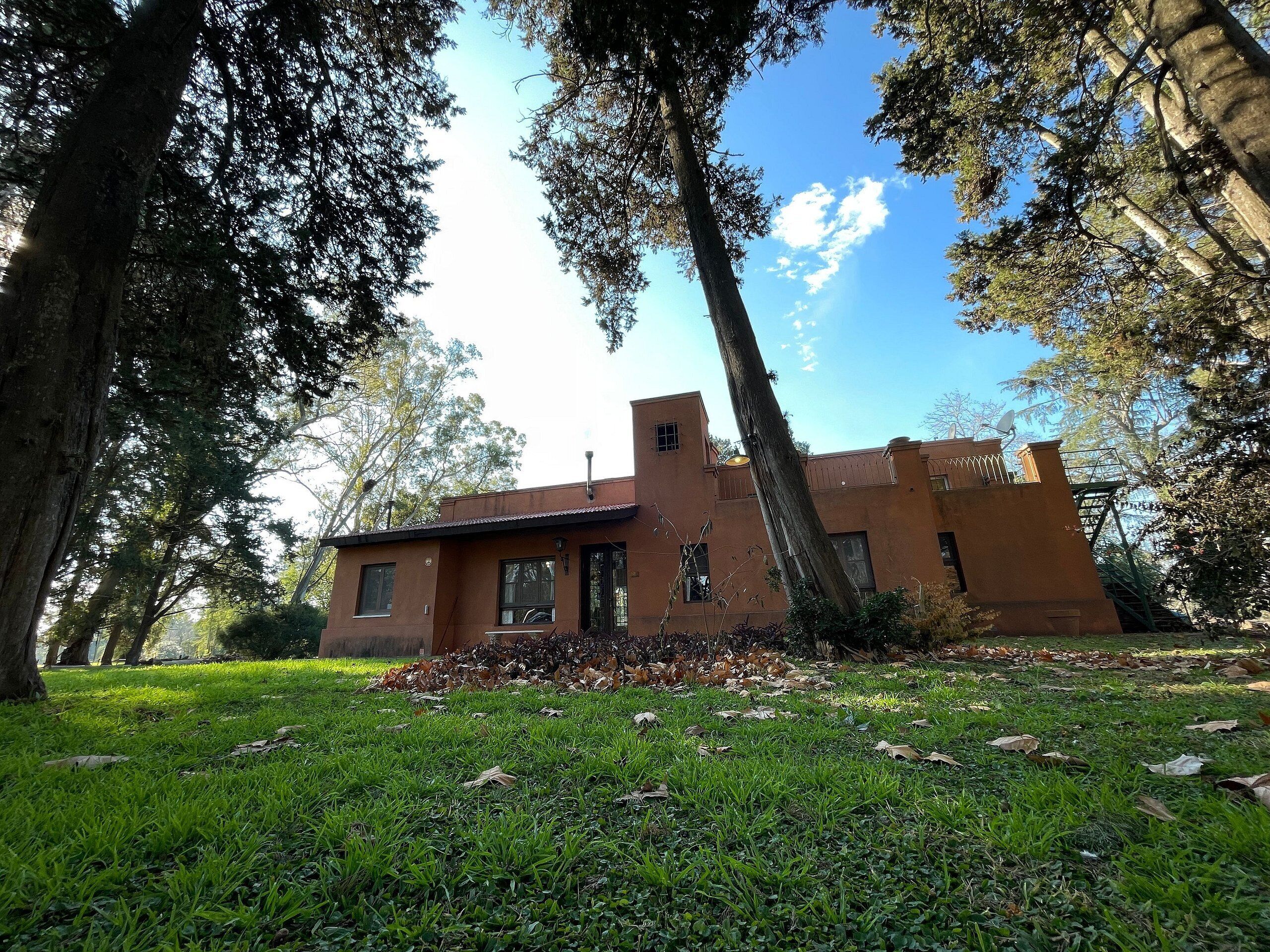 A rustic building with a flat roof, surrounded by trees and a grassy area.