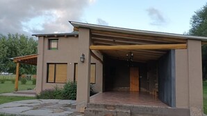 A modern house with a covered patio, a small garden, and a wooden pergola.