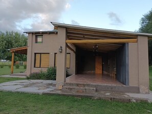 A modern house with a covered patio, a small garden, and a wooden pergola.