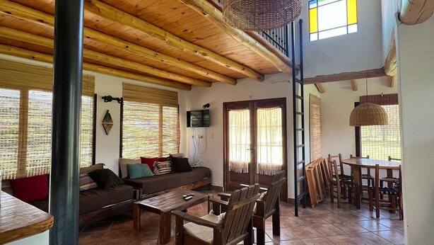 A spacious living area with a wooden staircase, a dining table with chairs, and a fireplace.