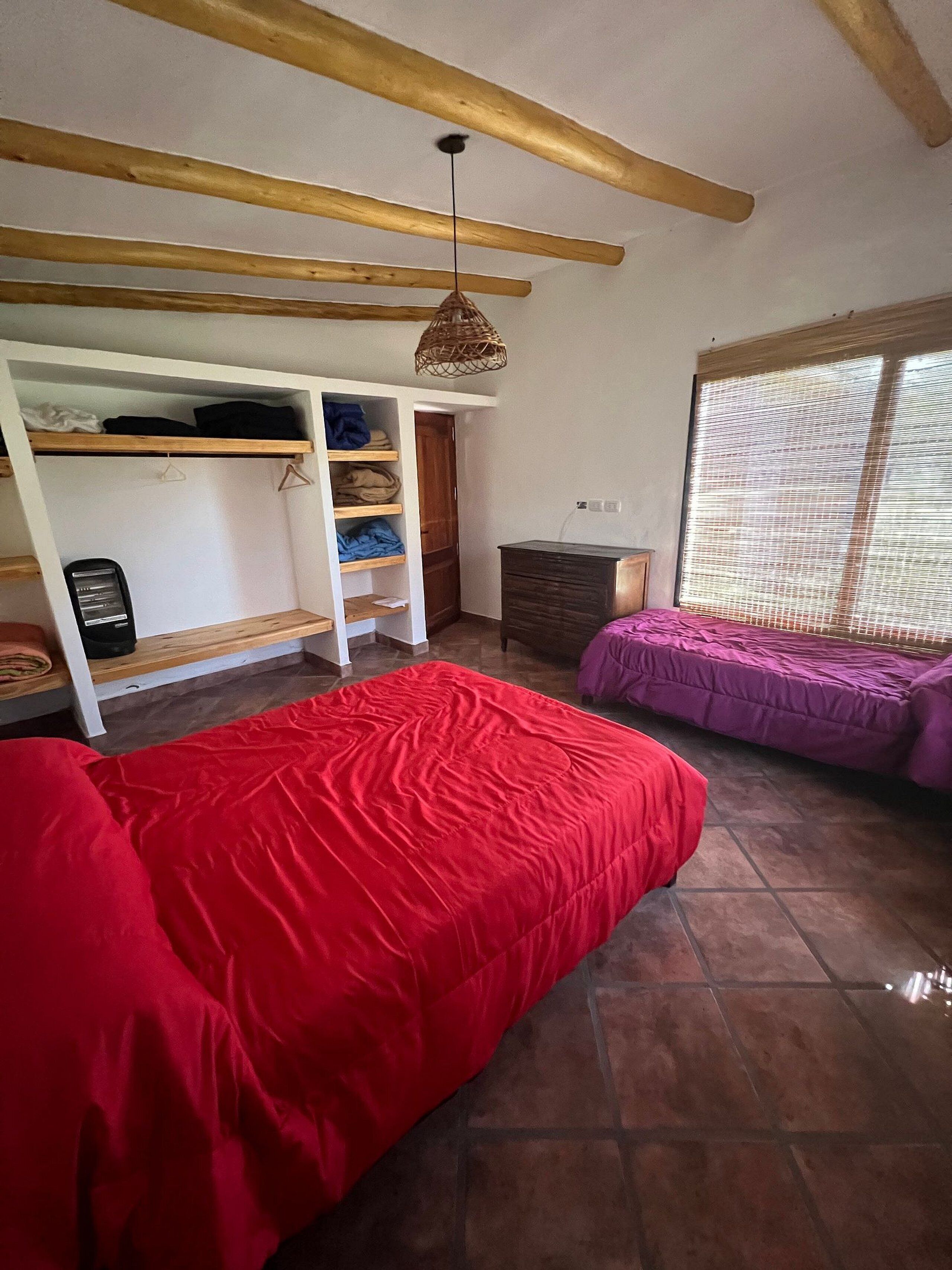 Un dormitorio con dos camas, un armario y una ventana con persianas.