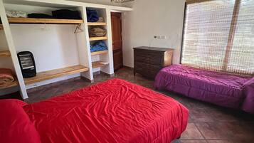 Un dormitorio con dos camas, un armario y una ventana con persianas.