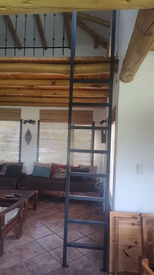 Una habitación con techo de madera, un conjunto de sofás, una mesa de centro y una escalera.