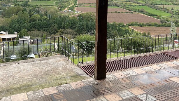 A covered outdoor area with a view of a valley and mountains.