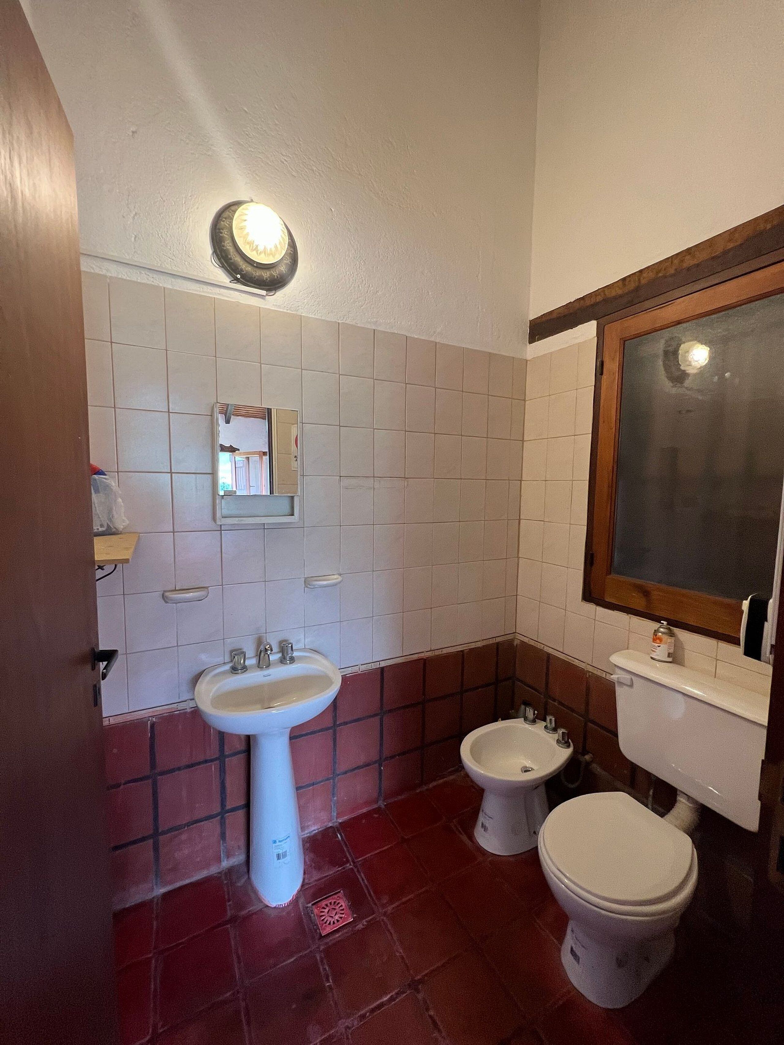 A bathroom with a white sink, two toilets, and a mirror.