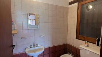 A bathroom with a white sink, two toilets, and a mirror.