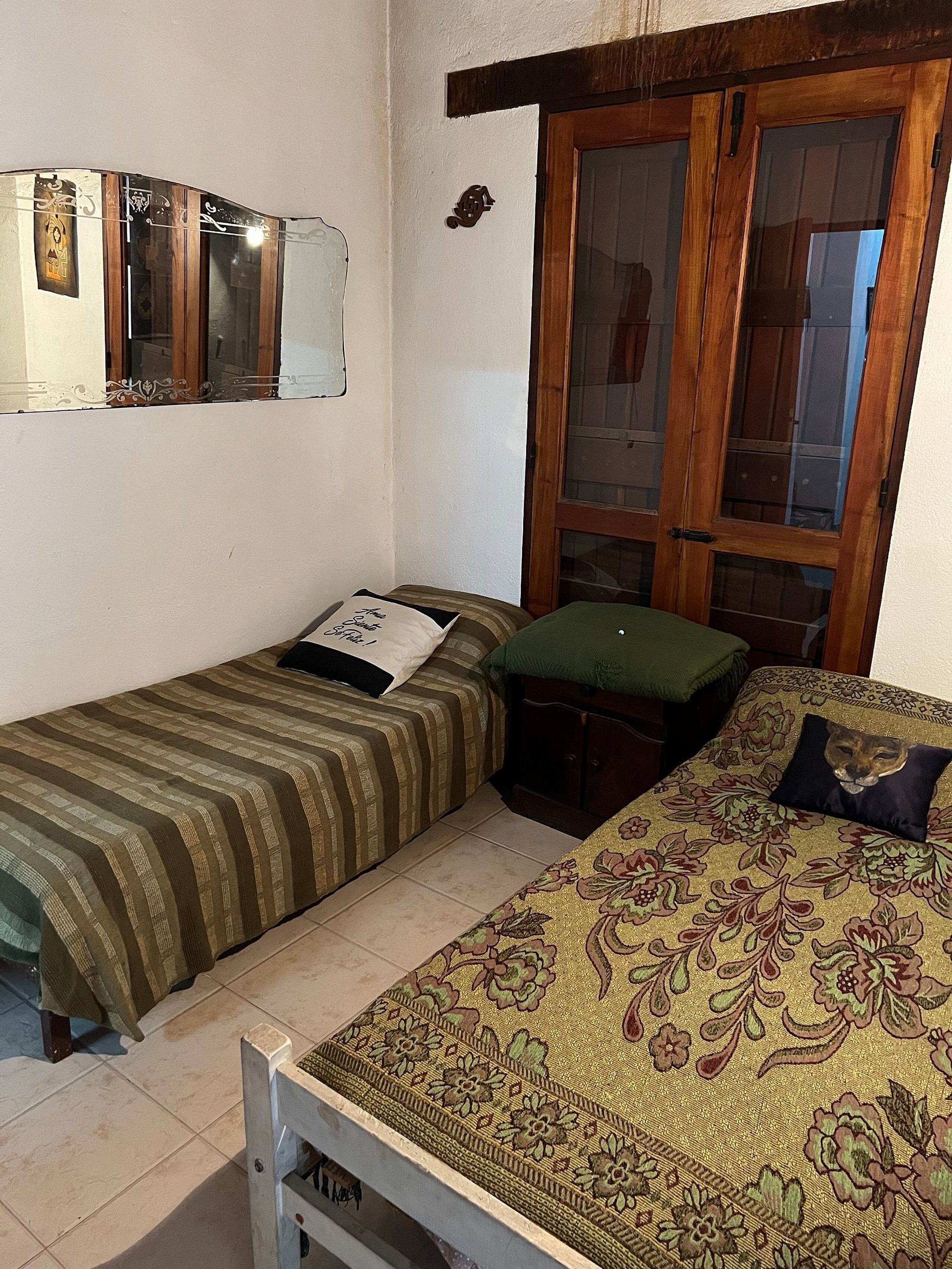 Une chambre avec deux lits, une armoire en bois et une fenêtre avec des volets en bois.