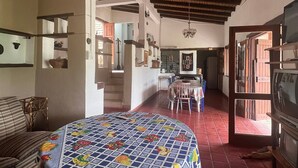 A spacious room with a large bed, a dining area, and a television.