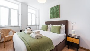 Et pænt indrettet hotelværelse med en stor seng, et natbord med lampe, en stol og et billede på væggen.
