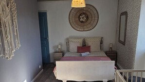 Ein Schlafzimmer mit Bett, Nachttischen, einer Hängeleuchte, einer Wanddekoration und einer Treppe.