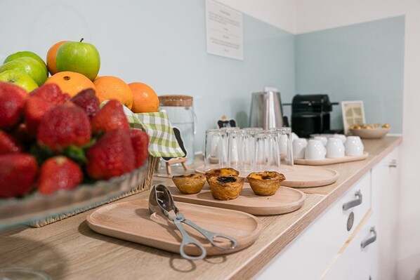 A kitchen counter with fresh fruits, tea cups, and pastries.