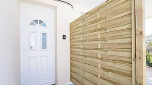 Una puerta blanca con un ventanal pequeño y una cerradura electrónica, junto a una pared de madera con tablones horizontales.