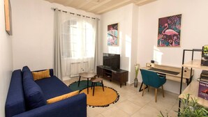 Sala de estar con sofá, televisión y escritorio con silla.