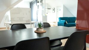 Moderni kokoustila, jossa on tumma puinen pöytä, mustat tuolit ja lasitasoinen pöytä, jonka päällä on pieni kasvi.