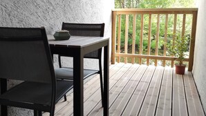 A wooden deck with a table and chairs, a potted plant, and a view of greenery through a wooden railing. - Studio Le Brivet City Center ☆ Parking ☆ Terrace (Pontchâteau)