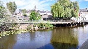 A river with a bridge, trees, and buildings in the background. - Studio Le Brivet City Center ☆ Parking ☆ Terrace (Pontchâteau)