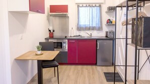 A compact kitchen with a microwave, oven, and sink. There is a small dining table with a chair. - Studio Le Brivet City Center ☆ Parking ☆ Terrace (Pontchâteau)