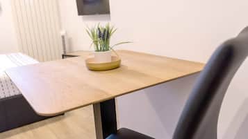 A modern room with a wooden table, a small potted plant, and a black chair.