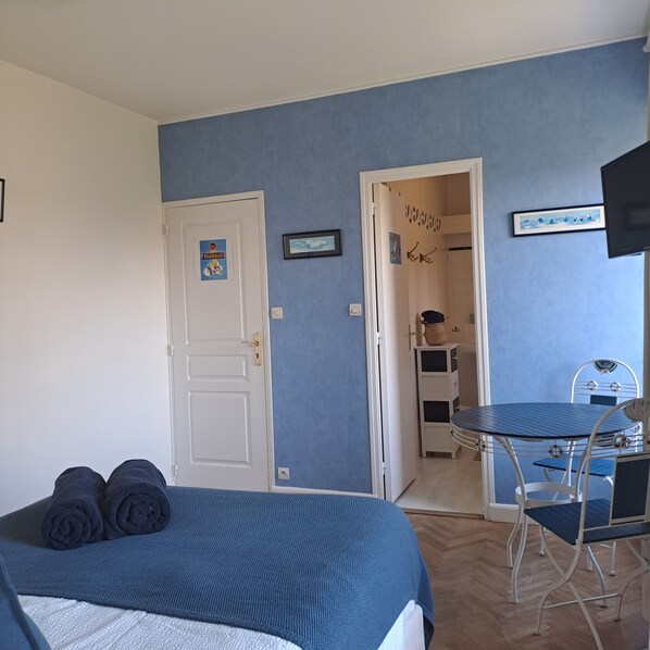 A bedroom with a bed, a desk, and a chair. There is a door with a sign, a framed picture, and a television on the wall. - Chambre d'hôtes le lac (Cherrueix)
