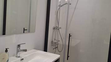 Une salle de bain moderne avec un lavabo blanc, un miroir et une douche.