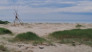 Een zandstrand met een klein, kaal gebouw.