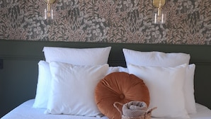 Een net opgemaakt bed met witte en bruine kussens, een geweven plaid en een decoratief hoofdbord.