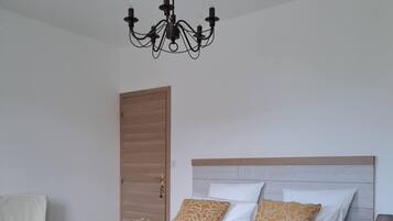 Un dormitorio con cama, mesita de noche, lámpara, silla, puerta y candelabro.
