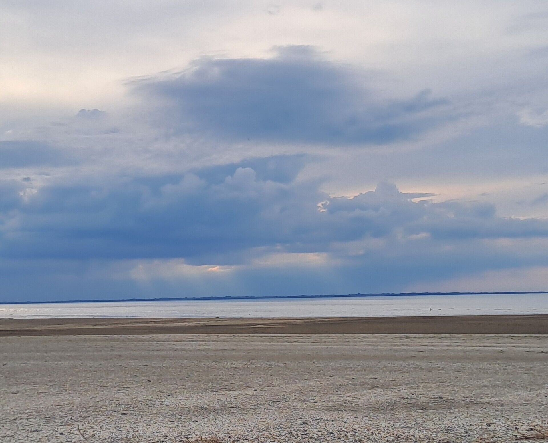 Une plage avec une vaste étendue de sable et un ciel nuageux.