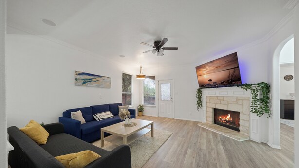 Un salon avec une cheminée, un canapé bleu et un ventilateur de plafond.