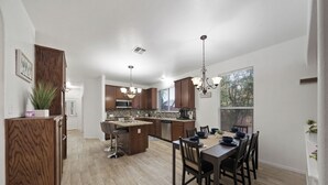 Une cuisine spacieuse dotée de meubles en bois, d’un îlot central et d’un coin repas avec une table et des chaises.