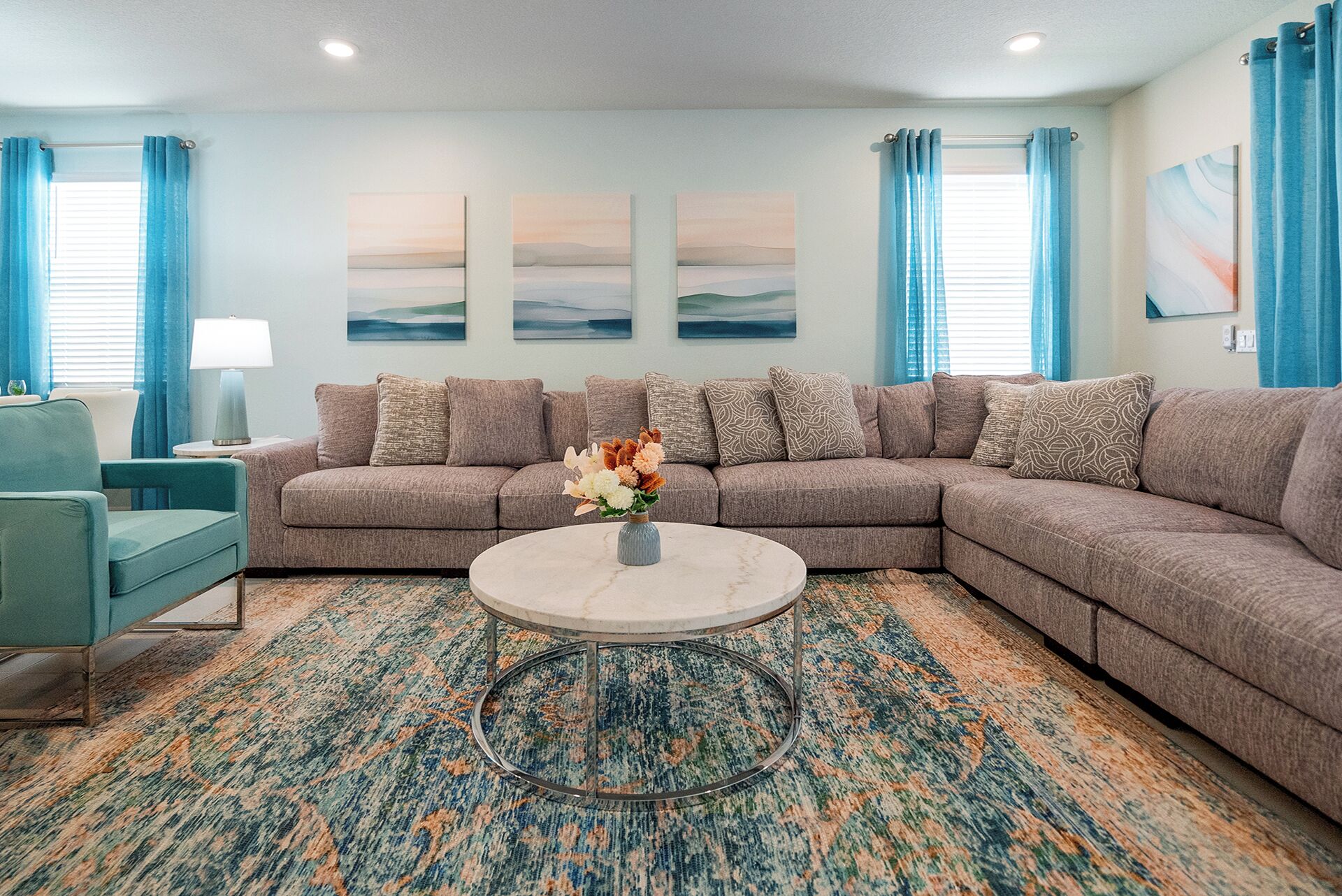 A living room with a sectional sofa, a round coffee table, and a patterned rug.