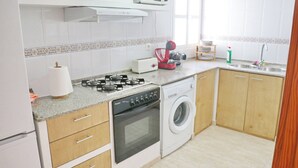 Cocina compacta equipada con estufa a gas, microondas, horno y lavadora.